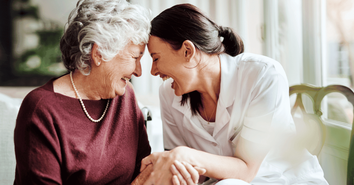 A woman and her grandma sit with their heads touching and smiling